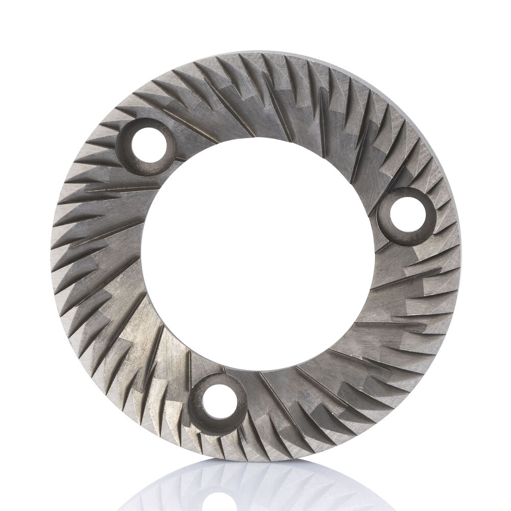Esta descripción del producto corresponde a una muela plana SVART UNIFORM de 58 mm, de forma circular, con ranuras radiales y tres orificios de fijación equidistantes cerca del centro. La superficie del disco presenta un relieve con motivos angulosos y marcados, lo que la hace ideal para el esmerilado. El fondo es blanco.