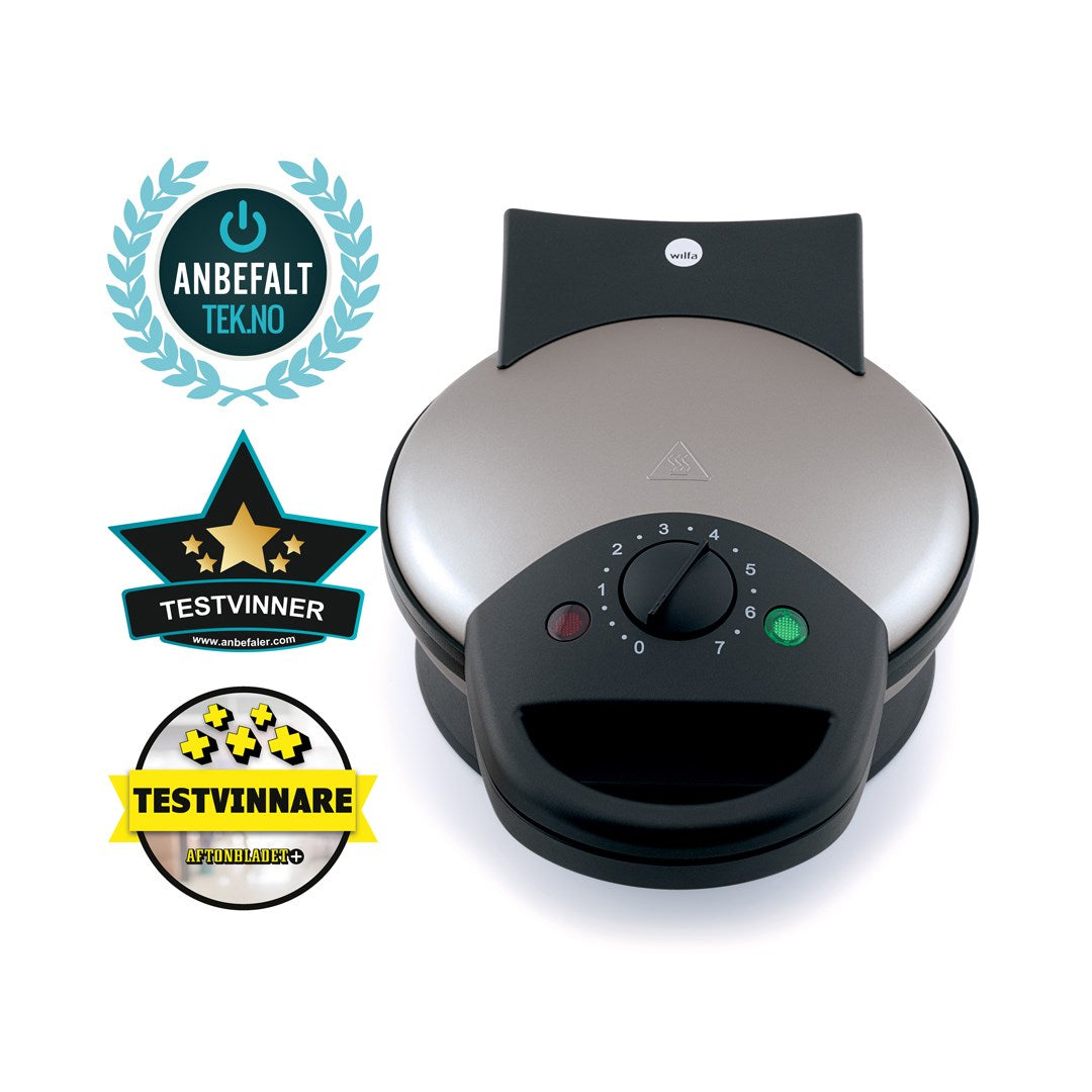 A BELL 23 with a black base and control dial. Featuring an adjustable thermostat for perfect waffles every time. Beside it are three award badges: a blue and teal circular badge reading "ANBEFALT TEK.NO," and two star-shaped badges reading "TESTVINNER" and "TESTVINNARE.