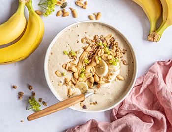 Banana and peanut smoothie bowl topped with peanuts, banana and granola