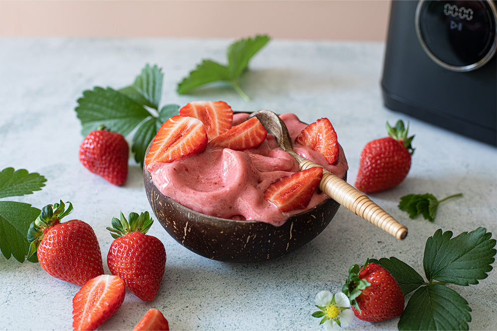 Strawberry nice cream served in a coconut shell bowl with fresh strawberries