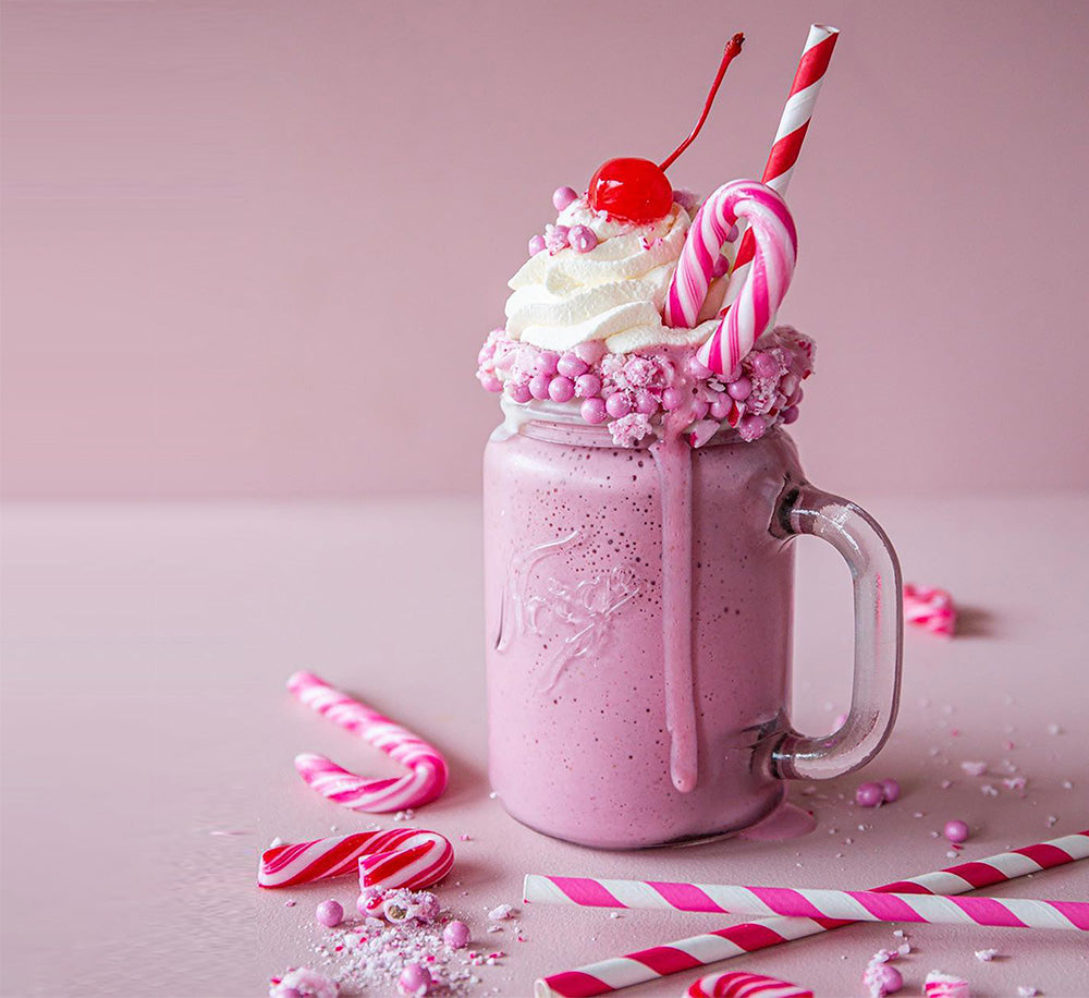Strawberry Christmas milkshake topped with whipped cream, candy canes and cherry