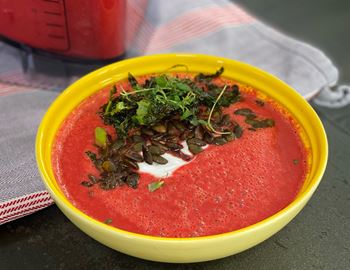 Bowl of red beetroot soup topped with herbs and crème fraîche