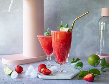Two glasses of virgin strawberry daiquiri with strawberries, lime and mint leaves