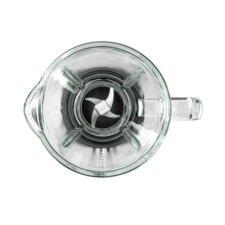 A black ESSENTIAL 1800 AUTO with a powerful 1800 W motor is filled with assorted ingredients, including spinach, bananas, and mango chunks. The borosilicate glass jar sits securely on the black base with a control dial and buttons. The lid is on, complete with a black stirring tool attached to it.