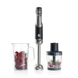 A black and silver ESSENTIAL POWER set with a powerful motor and stepless speed control, featuring three components: the blender handle, a clear measuring pitcher filled with chopped red onions, and a clear food processor attachment containing chopped vegetables, including red onions and green peppers.