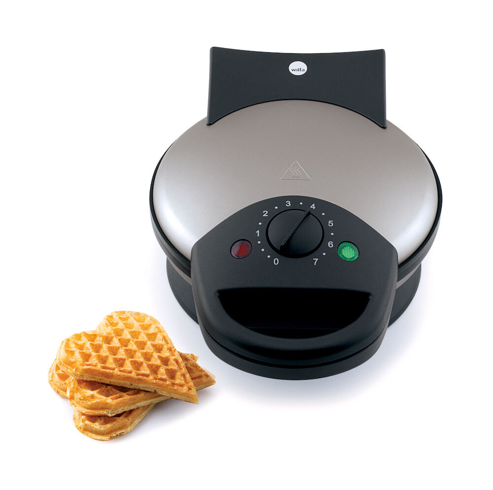 A BELL 23 with a black base and control dial. Featuring an adjustable thermostat for perfect waffles every time. Beside it are three award badges: a blue and teal circular badge reading "ANBEFALT TEK.NO," and two star-shaped badges reading "TESTVINNER" and "TESTVINNARE.